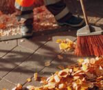 Janitor cleaner sweeping autumn leaves on the street